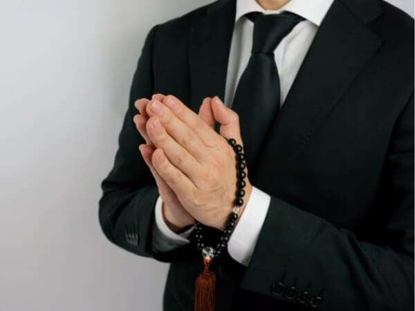 数珠をつけて合掌する人